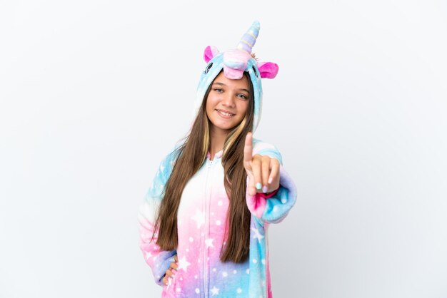 Niña caucásica con pijama de unicornio aislada de fondo blanco mostrando y levantando un dedo