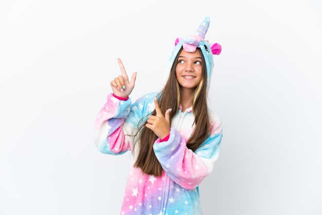 Niña caucásica con pijama de unicornio aislada de fondo blanco señalando con el dedo índice una gran idea