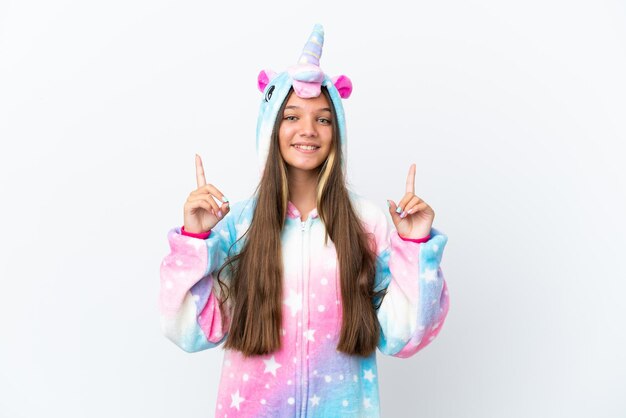 Niña caucásica con pijama de unicornio aislada de fondo blanco señalando una gran idea