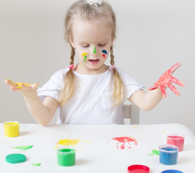 Niña caucásica que pinta con las manos coloridas Pinta en casa Educación temprana Preparación para el desarrollo de la escuela preescolar Juego de niños