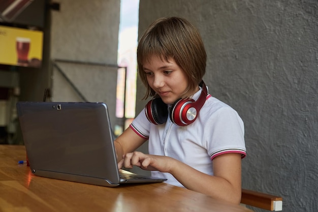 niña caucásica sentada en la mesa estudiando con latop educación en línea