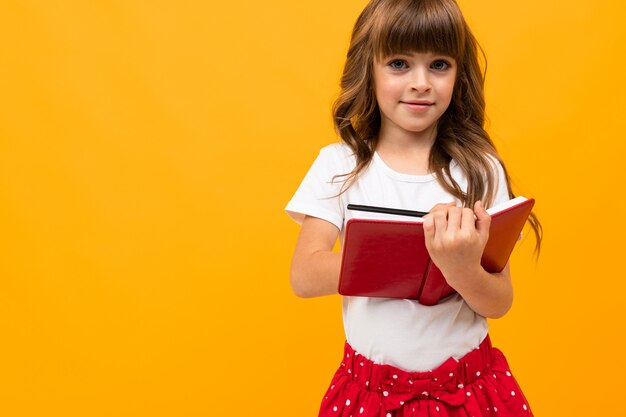 Niña caucásica sosteniendo un libro en manos en amarillo