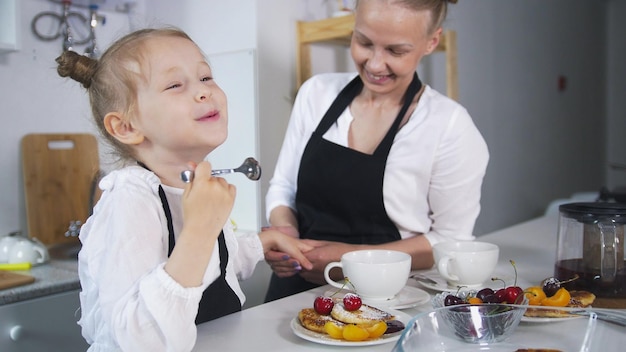 Niña caucásica con su madre cocinando juntos en la cocina