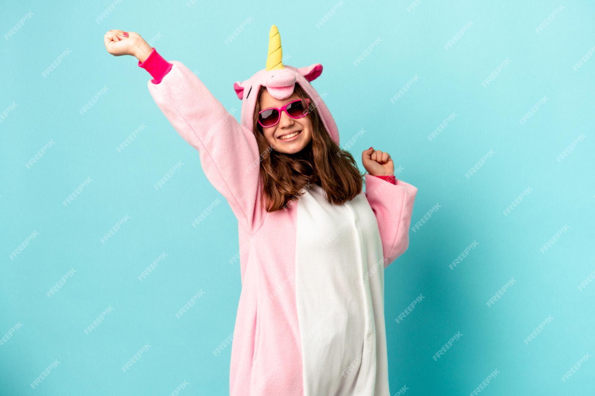 Niña caucásica vistiendo un pijama de unicornio aislado sobre rosa Foto Premium