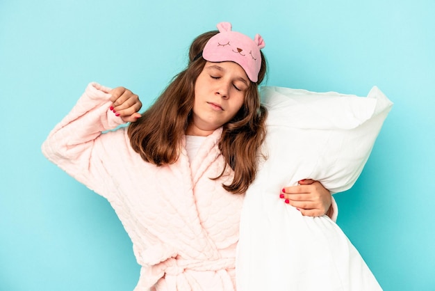 Niña caucásica yendo a dormir aislado sobre fondo azul.