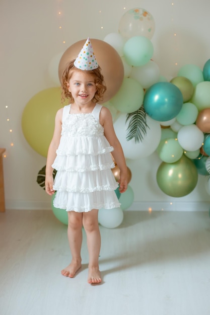 Una niña celebra su cumpleaños en el fondo de globos