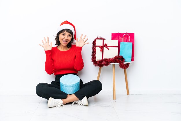 Niña celebrando la Navidad sentados en el suelo aislado en blanco bakcground contando diez con los dedos