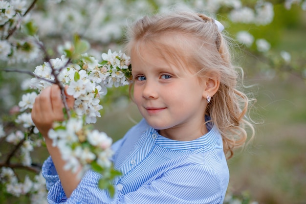 Una niña cerca de un árbol floreciente de primavera.