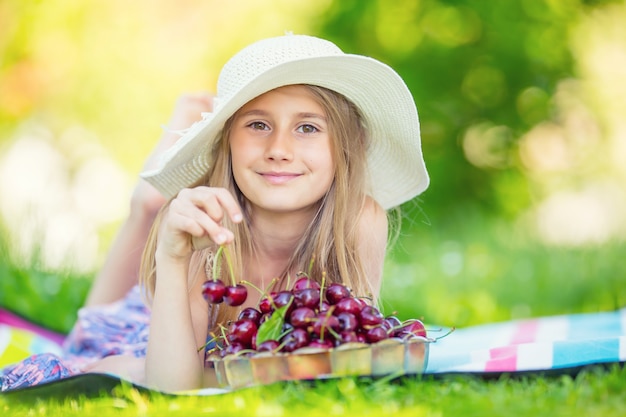Niña con cerezas frescas Retrato de una niña sonriente con un tazón lleno de cerezas frescas