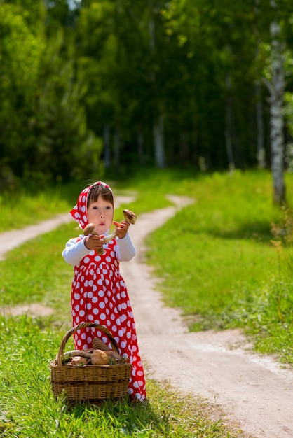 Niña con una cesta de setas en el bosque.