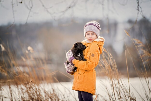 niña con una chaqueta amarilla abraza a un pequeño cachorro