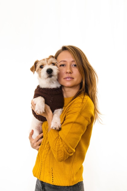 Una niña con una chaqueta amarilla sostiene un cachorro de Jack Russell Terrier. Aislar sobre fondo blanco