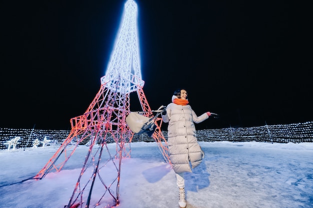 Una niña con una chaqueta gris en invierno con las luces del atardecer encendidas en la calle de Navidad