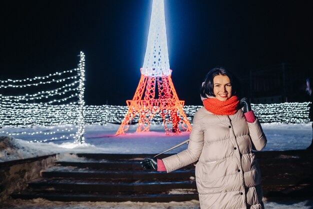 Una niña con una chaqueta gris en invierno con las luces del atardecer encendidas en la calle de Navidad