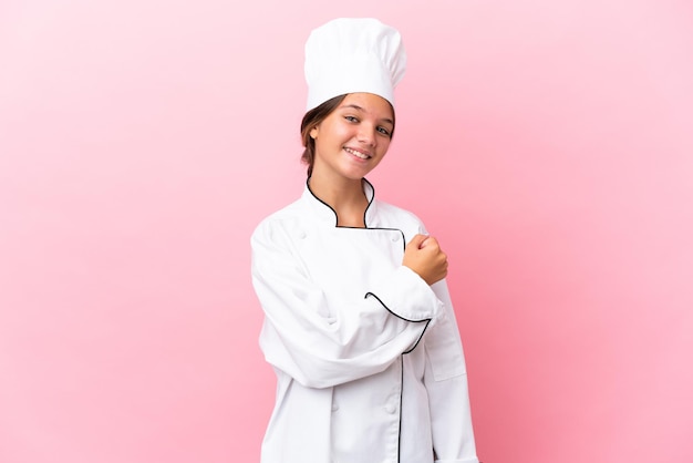 Niña chef caucásica aislada sobre fondo rosa celebrando una victoria