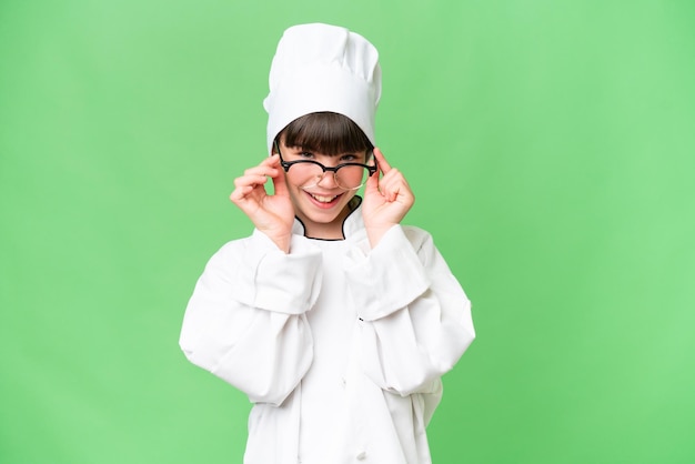 Niña chef caucásica sobre un fondo aislado con gafas y sorprendida