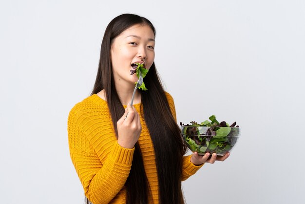 Niña china aislada sosteniendo un plato de ensalada con expresión feliz