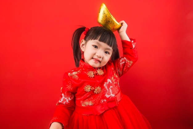 Una niña china celebra la Fiesta de la Primavera con lingotes de oro. Traducción china de lingotes de oro: riqueza de lingotes de oro