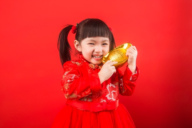 Una niña china celebra la Fiesta de la Primavera con lingotes de oro. Traducción china de lingotes de oro: riqueza de lingotes de oro