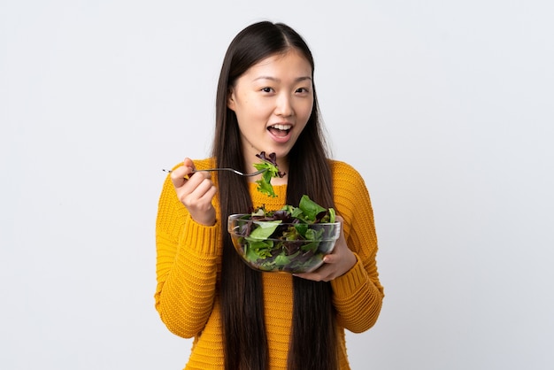 Niña China comiendo ensalada aislado