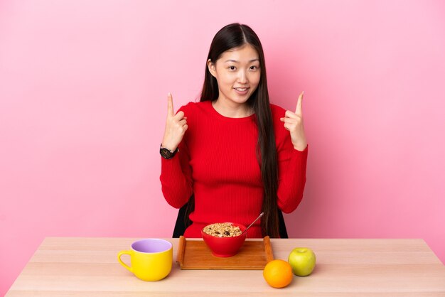 Niña china desayunando en una mesa apuntando hacia una gran idea