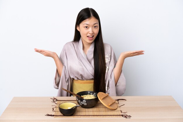 Niña china con kimono y comiendo fideos con expresión facial de sorpresa