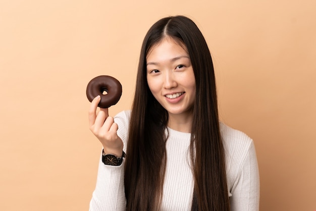 Niña china sobre antecedentes aislados sosteniendo una rosquilla y feliz