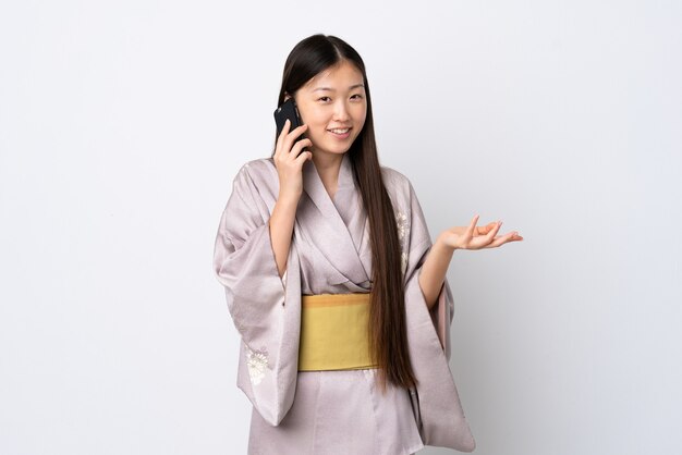 Niña china vistiendo kimono más aislado manteniendo una conversación con el teléfono móvil con alguien