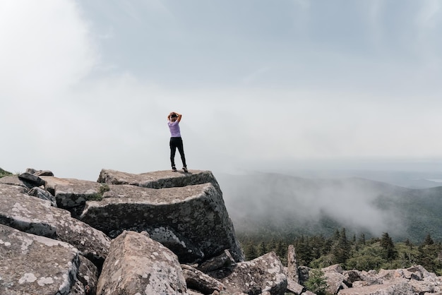 Una niña en la cima del monte Pidan mira un hermoso valle montañoso en la niebla en verano Viajes y turismo Senderismo