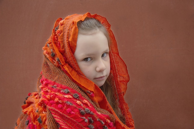 Una niña de cinco años con un pañuelo rojo. Ella está un poco triste.