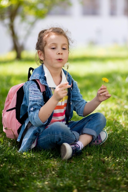 Una niña de cinco años paseando Es primavera afuera y el sol brilla Una niña sostiene un diente de león