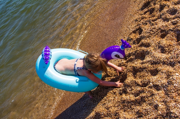 Una niña con un círculo inflable sale del mar a la orilla.