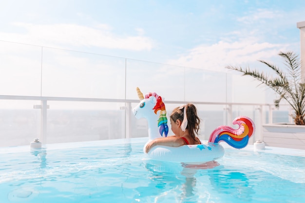 Niña en un círculo de unicornio en una elegante piscina con el fondo del mar