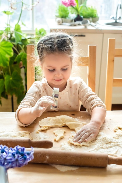 Niña cocina en casa en una cocina luminosa un niño revuelve harina en la mesa bebé ayuda a mamá y se ríe