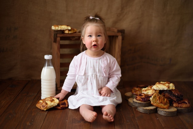 Niña en la cocina come pasteles dulces.