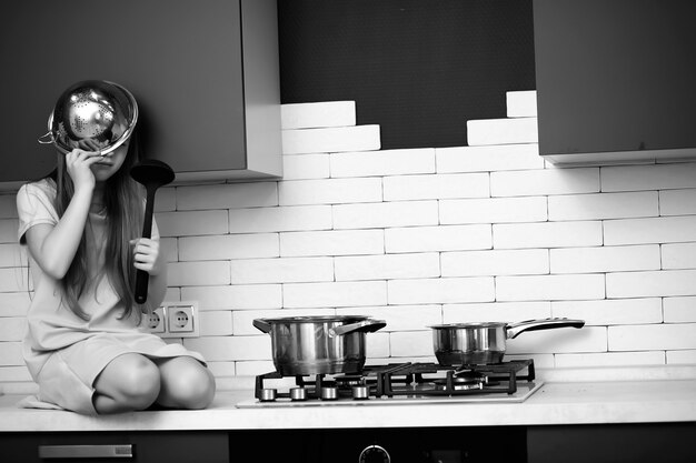 Foto niña en la cocina con utensilios de cocina