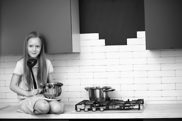 Niña en la cocina con utensilios de cocina