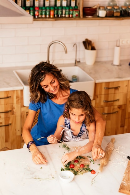 Niña cocinando con su madre en la cocina. Concepto de chef infantil.