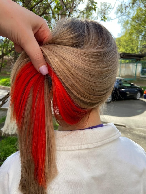 Foto una niña con una cola roja está atada a su cabello.