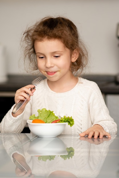 Una niña come una ensalada de verduras frescas El concepto de alimentación saludable Alimentos saludables Infancia