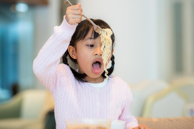 La niña come fideos instantáneos