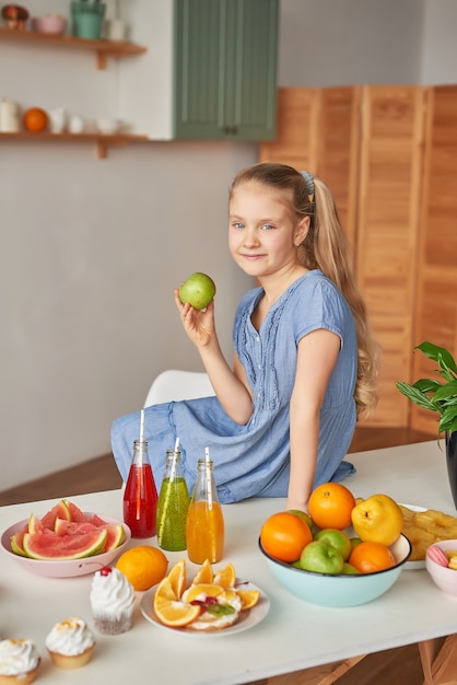 Niña come fruta en una mesa llena de comida