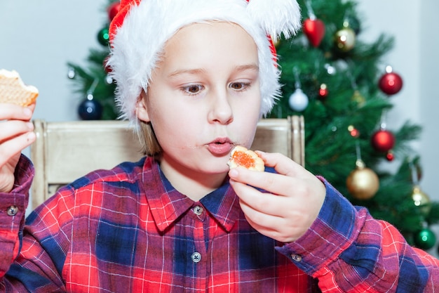 Niña come galletas con el telón de fondo del árbol de Navidad