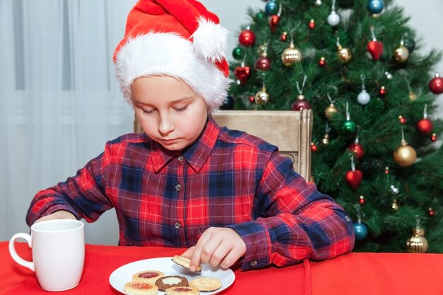 Niña come galletas con el telón de fondo del árbol de Navidad