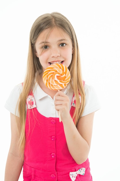 Foto niña come piruleta aislada en blanco niño pequeño disfruta de dulces en un palo sonrisa de niño feliz con caramelo remolino concepto de tienda de dulces infancia y felicidad humor dulce mi comida favorita