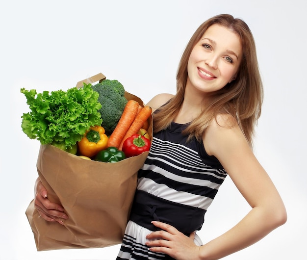 Niña con comestibles de verduras mujer joven sosteniendo una bolsa de comida de la tienda de comestibles