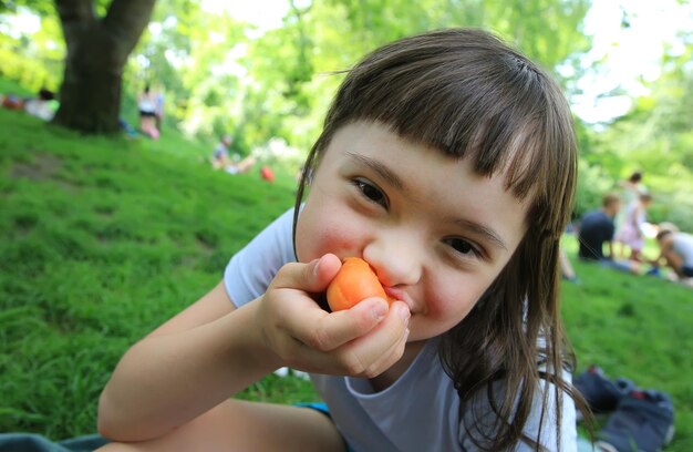 Niña comiendo albaricoque en el parque