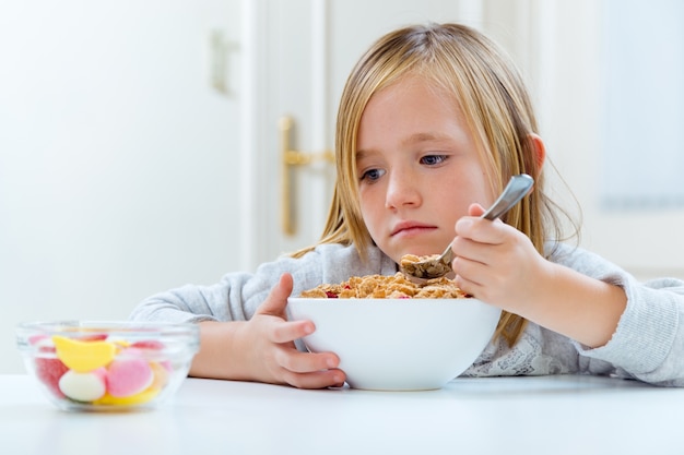 Niña comiendo cereales con leche dispuestos