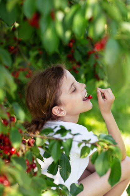 Niña comiendo cerezas en el jardín