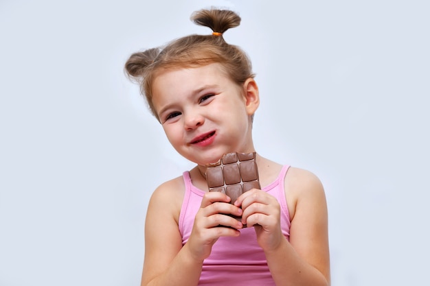 Foto niña comiendo chocolate aislado en blanco